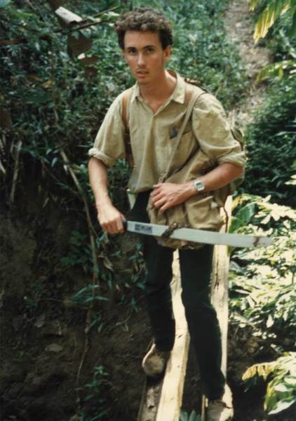 The author (Andrew Egan) crossing a log bridge
              on day one of the expedition with a newly-purchased
              machete